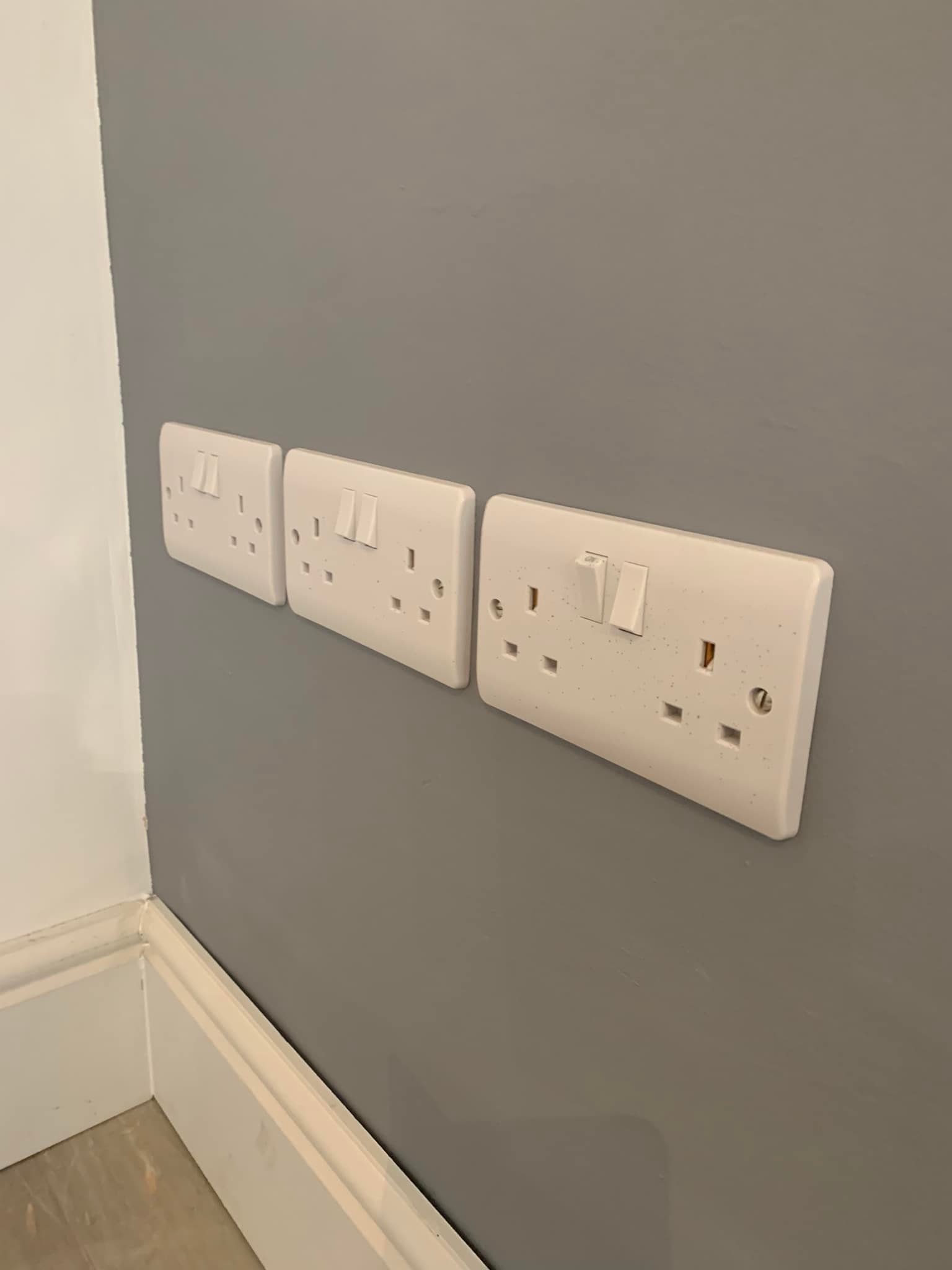 White sockets mounted on the wall near the skirting board